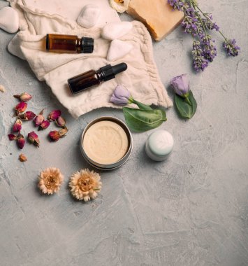 Açık gri arka planda bitkilerle ve çiçeklerle dolu bir şişe gerekli yağ. Üst görünüm, düz görünüm, kopyalama alanı