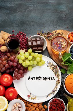 Koyu gri arka planda yüksek miktarda antioksidan içeren sağlıklı yiyecek seçimi. Temiz yeme kavramı. 