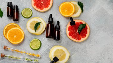 Açık gri arka planda narenciye aromalı bir şişe önemli aroma yağı. Üst görünüm, düz görünüm, kopyalama alanı