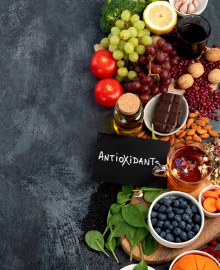 Koyu gri arka planda yüksek miktarda antioksidan içeren sağlıklı yiyecek seçimi. Temiz yeme kavramı. 