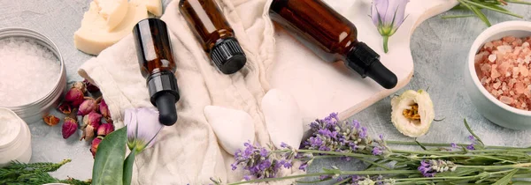 ライトグレーの背景にハーブや花とエッセンシャルオイルのボトル トップビュー フラットレイアウト パノラマ バナー — ストック写真