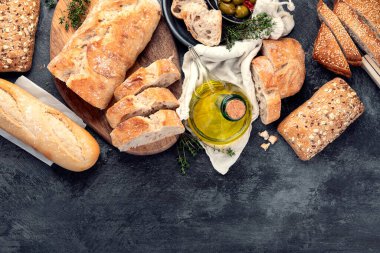 Koyu gri arka planda zeytinyağı ve zeytinli taze ekmek. Üst görünüm, alanı kopyala