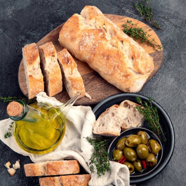 Koyu gri arka planda zeytinyağı ve zeytinli taze ekmek. Üst manzara, düz uzanma