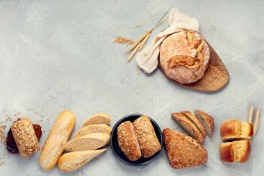 Açık gri arka planda çeşitli taze pişmiş ekmek türleri. Üst görünüm, düz görünüm, kopyalama alanı