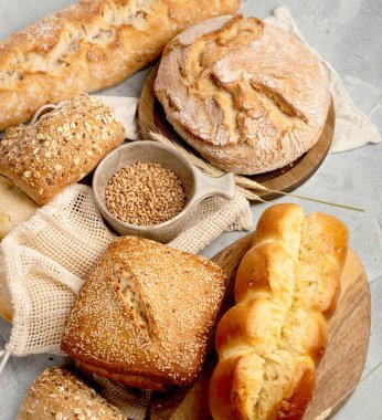 Açık gri arka planda çeşitli taze pişmiş ekmek türleri. Üst manzara, düz uzanma