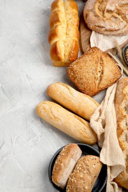 Açık gri arka planda çeşitli taze pişmiş ekmek türleri. Üst görünüm, düz görünüm, kopyalama alanı