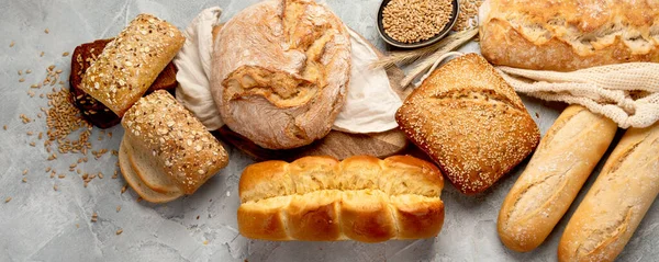 薄い灰色の背景に焼きたてのパンの様々なタイプ トップビュー フラットレイアウト パノラマ — ストック写真