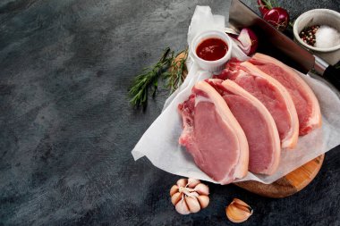 Koyu gri arka planda dilimlenmiş çiğ domuz eti. Organik gurme yemek konsepti. Üst görünüm, düz görünüm, kopyalama alanı