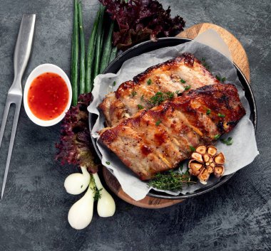 Koyu gri arka planda abur cubur ve sos ile kızarmış pirzola. Gurme yemek pişirme kavramı. Üst manzara, düz uzanma