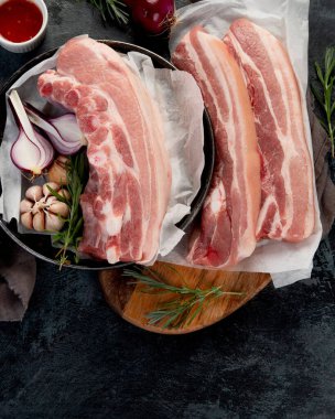 Koyu gri arka planda çiğ domuz göbeği. Organik gurme yemek konsepti. Üst görünüm, düz görünüm, kopyalama alanı