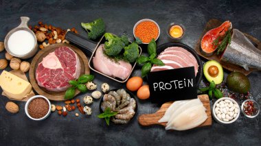 Koyu arkaplanda doğal protein kaynakları. Sağlıklı dengeli diyet kavramı. Üst manzara, düz uzanma