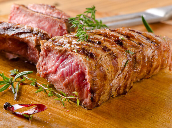 Grilled Beef steak on a cutting board with herbs