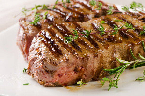 Beef steak with fresh herbs on white background