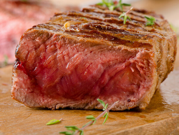 Grilled Beef steak on a cutting board with herbs
