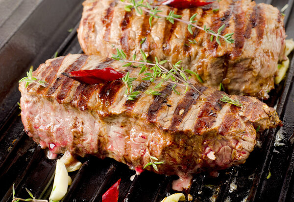 Beef steaks on grill pan with herbs and spices