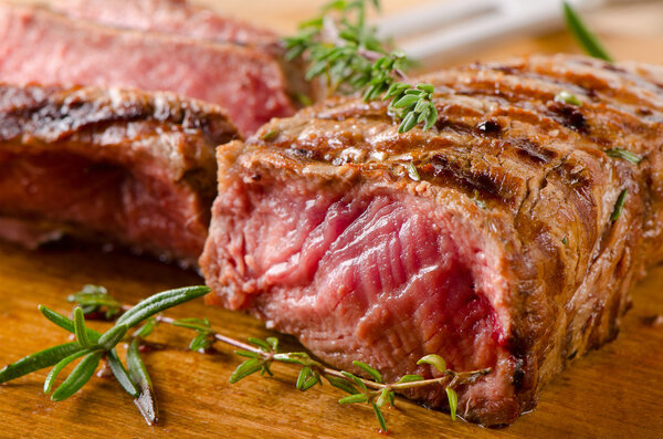 Grilled Beef steak on a cutting board with herbs