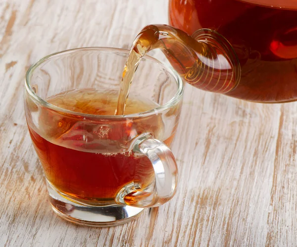 Té vertiendo en la taza de vidrio —  Fotos de Stock