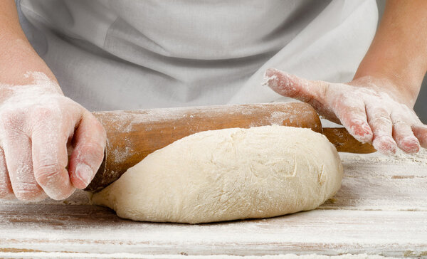 Hands preparing dough with rolling pin