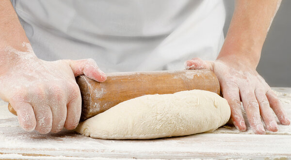 Hands preparing dough with rolling pin