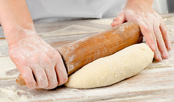 Hands preparing dough with rolling pin
