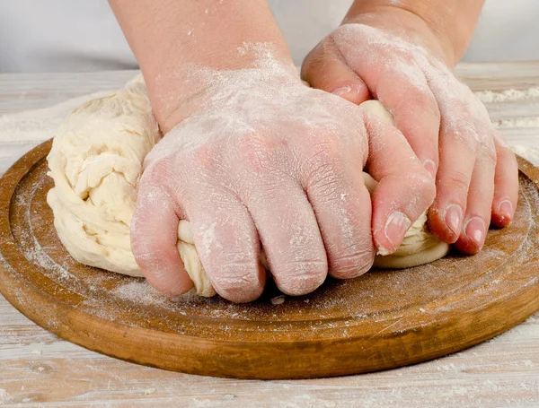 Hände bereiten Teig auf einem Holzbrett zu — Stockfoto