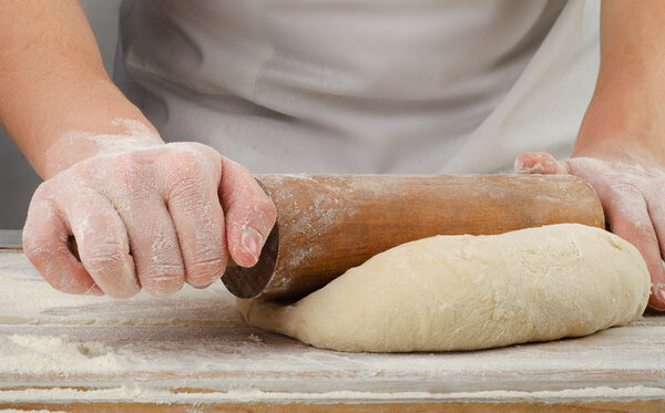 Hands preparing dough with rolling pin