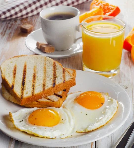 Ontbijt met twee gebakken eieren, toast, SAP en koffie. — Stockfoto