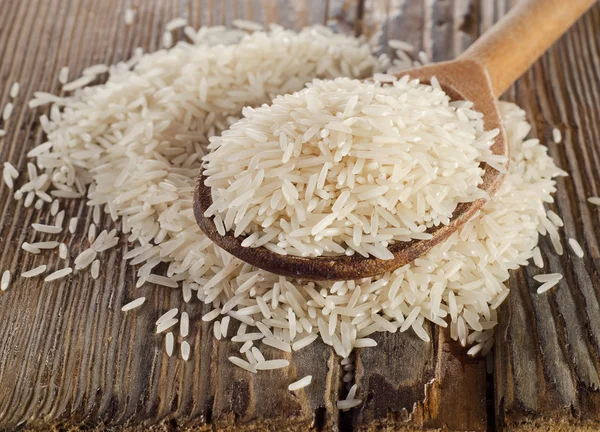 Uncooked rice in a wooden  spoon — Stock Photo, Image