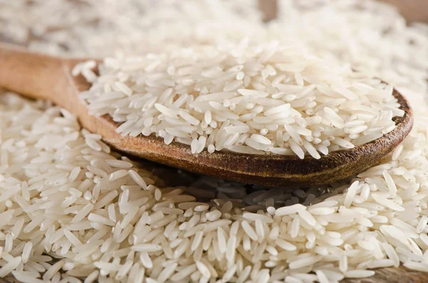 Uncooked rice in a wooden  spoon — Stock Photo, Image