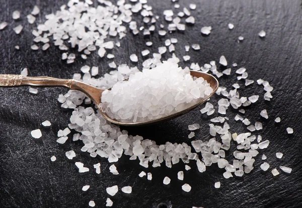 Salt in a spoon on  black background — Stock Photo, Image