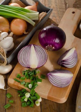 Kesme tahtasında taze soğanlar