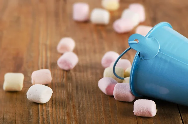 Sweet marshmallows spilling from  blue bucket. — Stock Photo, Image