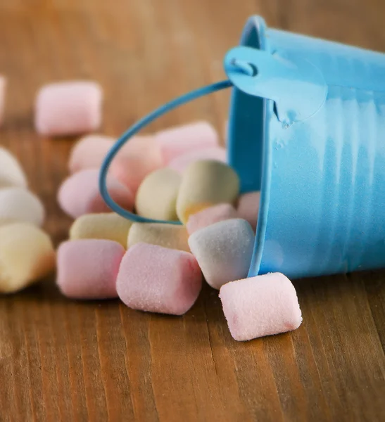 Sweet marshmallows spilling from  blue bucket. — Stock Photo, Image