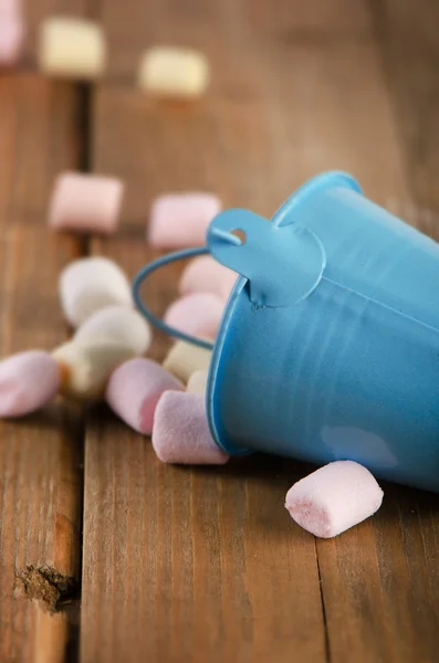 Sweet marshmallows spilling from  blue bucket. — Stock Photo, Image