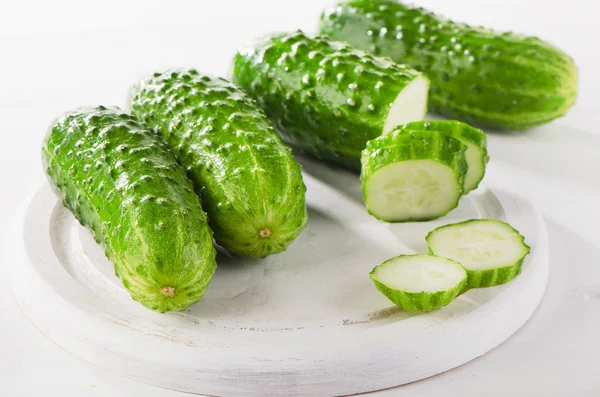 Fresh cucumbers on a white cutting board. — Stock Photo, Image