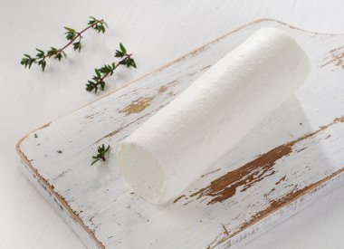 Keçi peyniri Beyaz ahşap masa üzerinde taze otlar ile