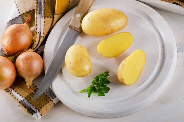 Frische Kartoffeln auf einem weißen Schneidebrett — Stockfoto