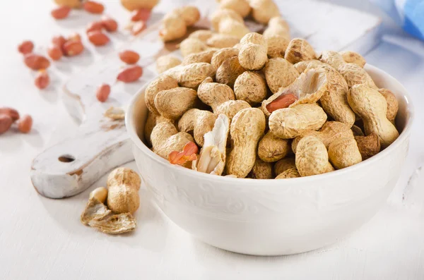 Amendoim em conchas em uma tigela branca . — Fotografia de Stock