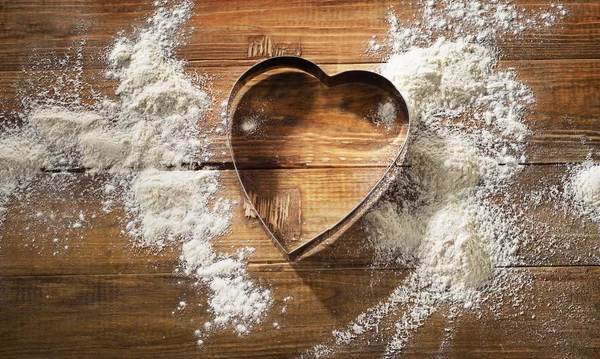 Cortador de galletas en forma de corazón y harina blanca — Foto de Stock