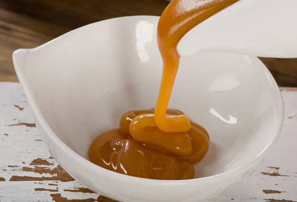 Caramel sauce pouring in bowl.