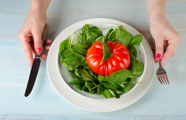 Женские руки с зеленым салатом и помидорами — стоковое фото