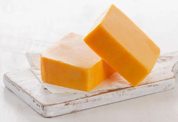 まな板の上のチーズ白い木製のまな板にチェダー チーズ。選択と集中 — ストック写真