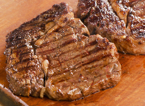 Beef steaks on wooden board. Selective focus