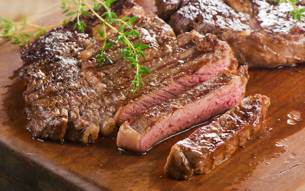 Beef steaks on wooden board. Selective focus