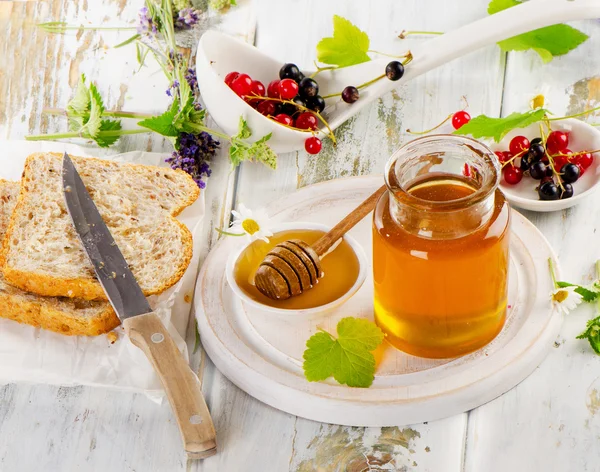Мед в стеклянной банке, ягоды и тосты — стоковое фото