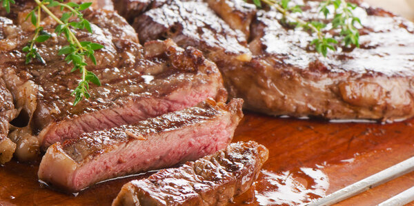 Close-up of beef steaks on wooden board.