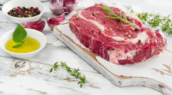 Filetes de ribeye crudos en una tabla de cortar . —  Fotos de Stock