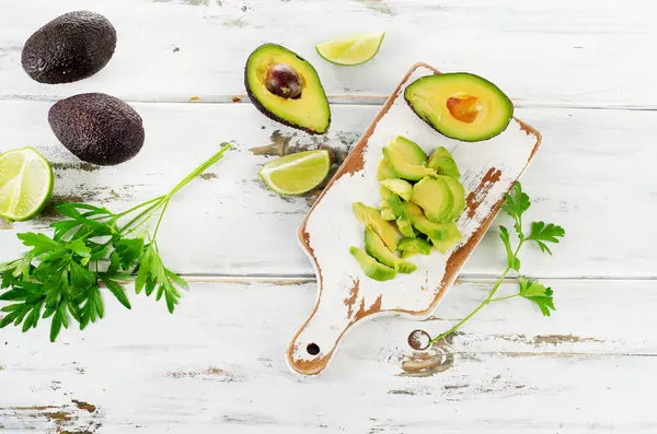 Beyaz kesme tahtası üzerinde avokado dilimlenmiş. — Stok fotoğraf