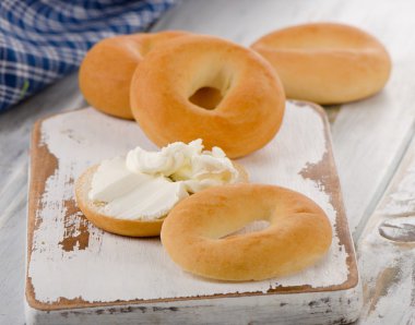 Bagels with cream cheese on a wooden board.  clipart