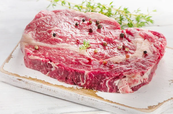 Bife de carne na placa de corte de madeira branca . — Fotografia de Stock